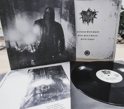 Disco de vinil preto com capa e encarte em cinza e branco, texto gótico e imagem de pessoa encapuzada.