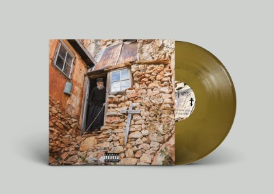 Disco de vinil amarelo com capa mostrando homem e casa rústica de pedra e tijolo.