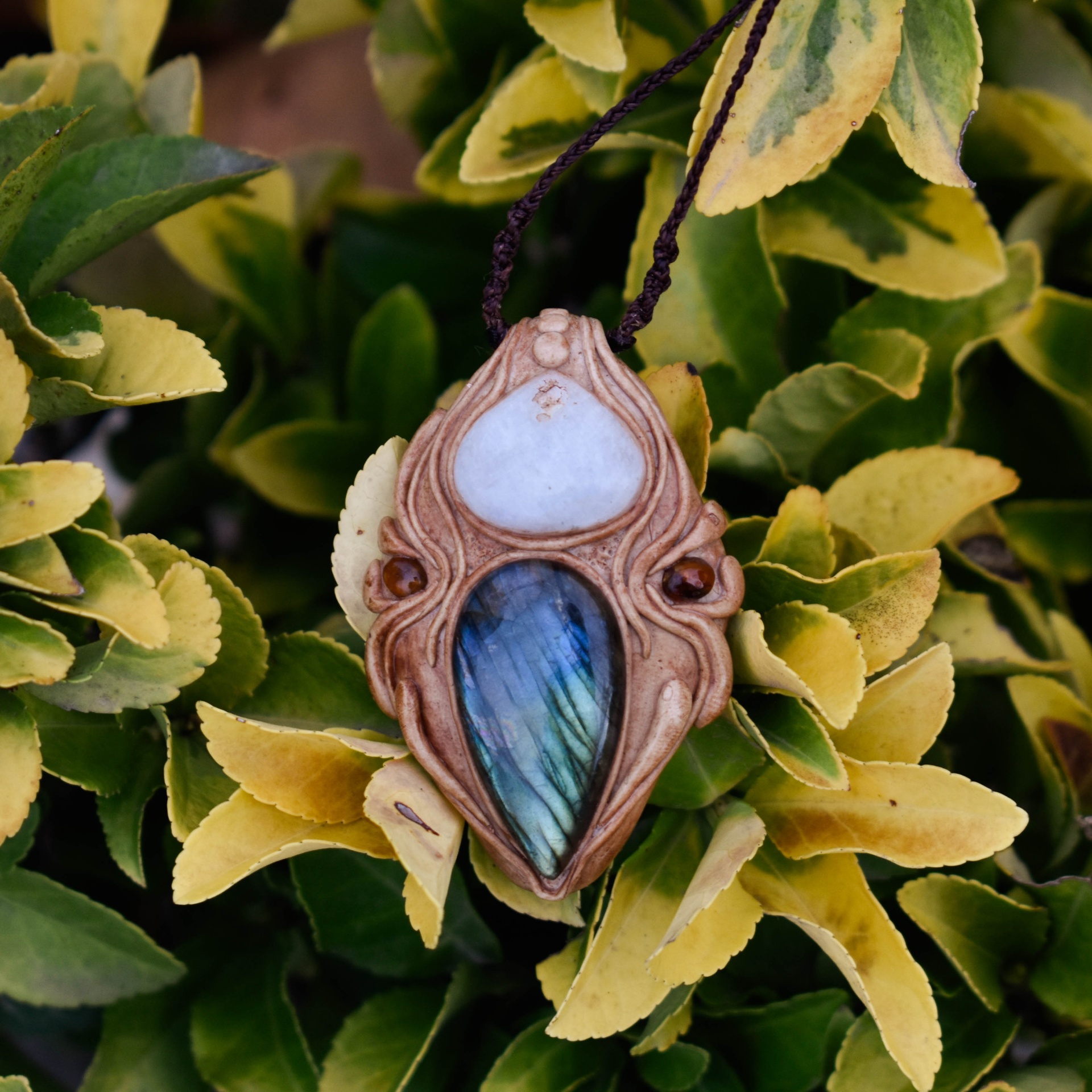 Amuleto Dharma com Pedra da Lua, Turmalinas e Labradorite Colar com pendente artesanal em madeira e pedras coloridas pendurado em folhas