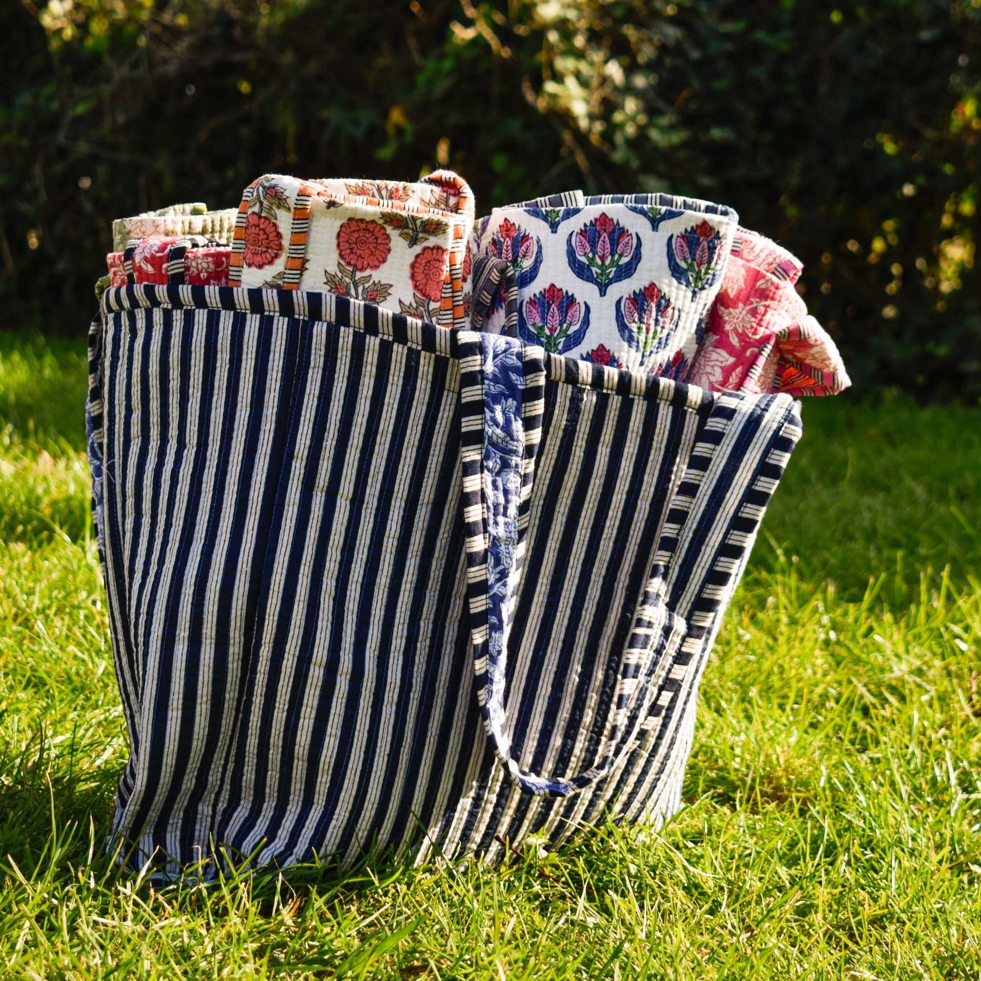 Mala riscada azul e branca com tecidos florais sobre relva