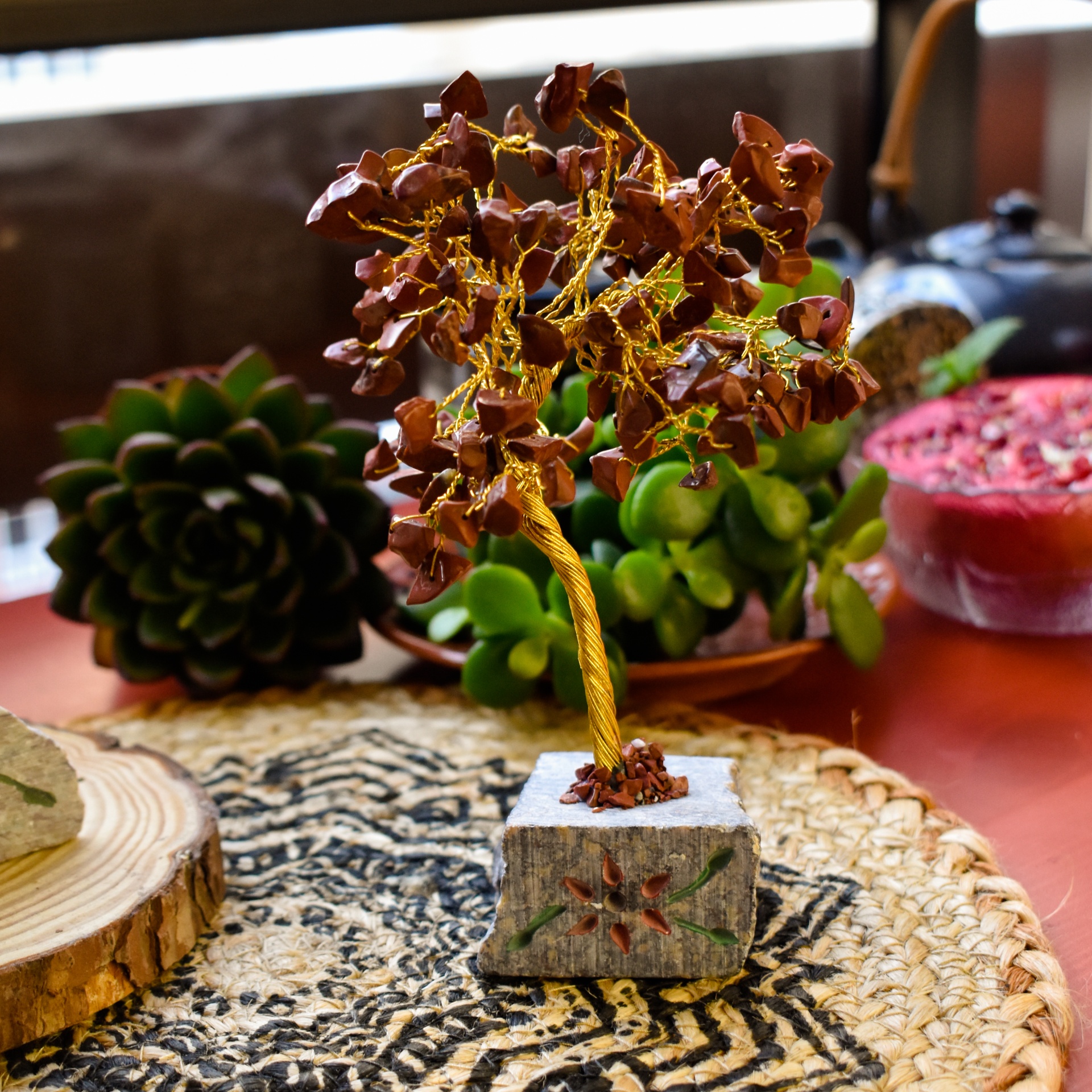 Miniatura de árvore decorativa com folhas castanhas e base de pedra sobre tapete com padrão em ambiente interior