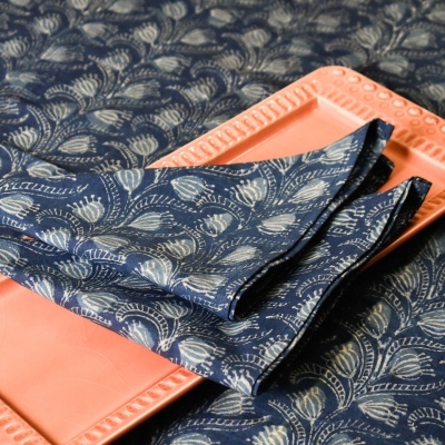Guardanapo azul escuro com padrão de folhas em prato salmão retangular com fundo azul e branco