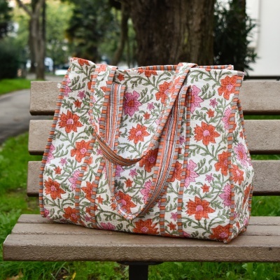 Mala de tecido floral com alças às riscas num banco de madeira
