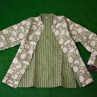 Casaco floral bege com forro verde listrado aberto sobre superfície verde