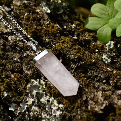 Colar com pendente de pedra rosa hexagonal sobre musgo e casca de árvore