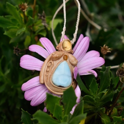 Colar pendente artesanal com pedra azul claro pendurado em flor cor de rosa