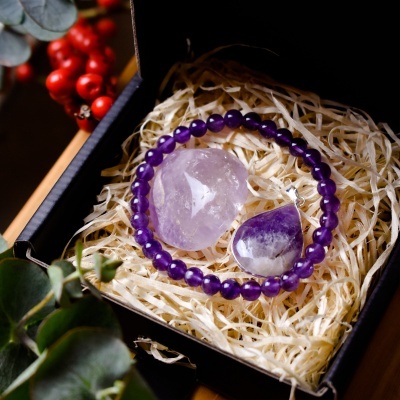 Caixa preta com pulseira roxa, pedra polida e pingente roxo bruto