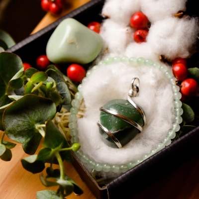 Pendente de pedra verde e pulseira numa caixa preta com decoração de bagas vermelhas