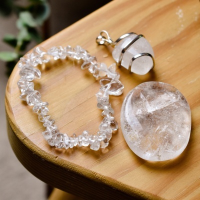 Pulseira de pedras transparentes, pingente com pedra branca e pedra oval sobre madeira