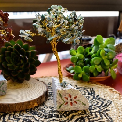 Decoração de árvore em pedra e metal dourado sobre base de pedra e tapete geométrico