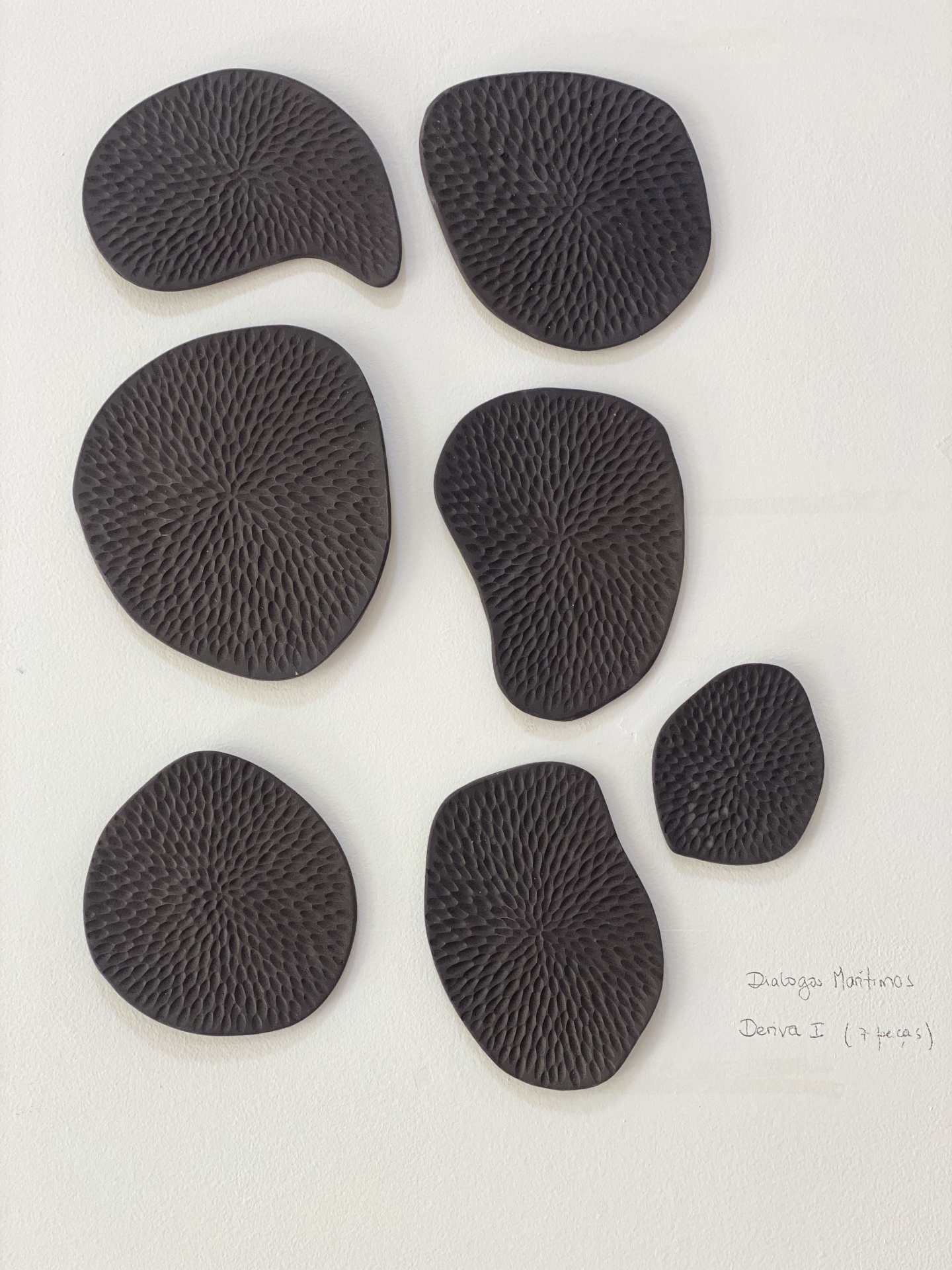 Escultura Diálogos Marítimos Peças decorativas pretas texturizadas em fundo branco com texto à mão.