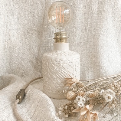 Lâmpada decorativa com base branca texturizada e flores secas sobre fundo bege