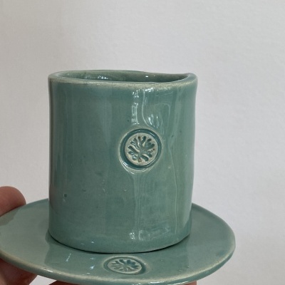 chávena e pires verdes em cerâmica com relevo circular de flor