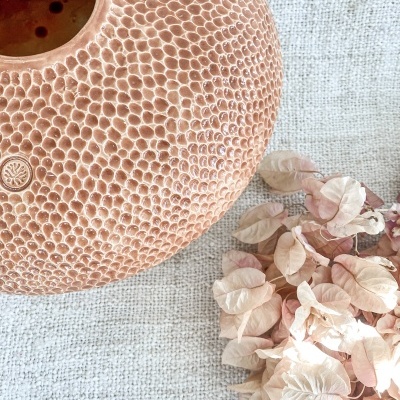 Vaso de cerâmica castanho claro com padrão hexagonal e flores secas cor de rosa