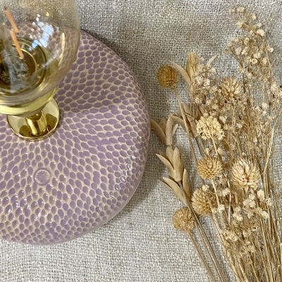 Base de candeeiro rosa com padrão texturizado, lâmpada visível e flores secas em tecido bege