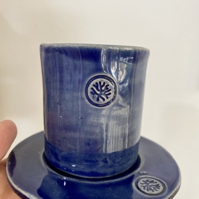 Conjunto de chávena e pires azul escuro com símbolo circular em relevo