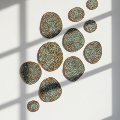 Peças decorativas circulares e ovais com padrão verde e castanho numa parede branca