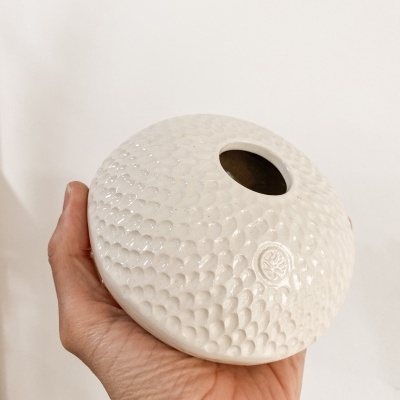 Vaso cerâmico branco com textura de escamas e buraco redondo no topo