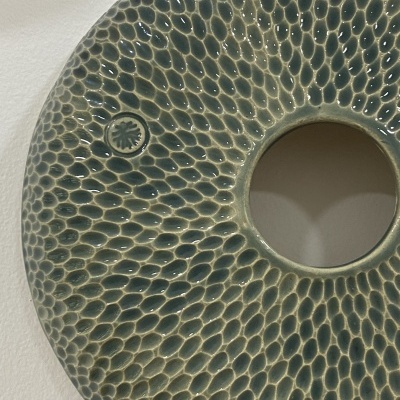 anel decorativo verde escuro de cerâmica com padrão em relevo e buraco central