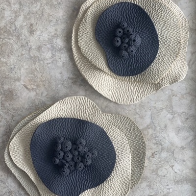 Pratos decorativos com textura creme e azul escuro sobre superfície de pedra