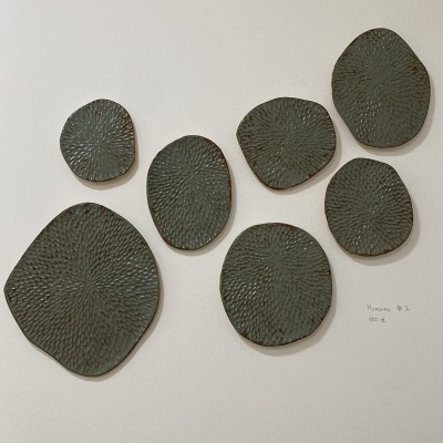 Placas cerâmicas decorativas cinza com textura circular em parede branca