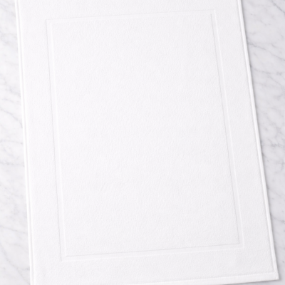 Tapete de banho branco sobre superfície de mármore cinzento