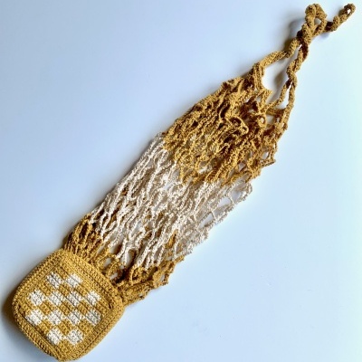 Rede de croché amarela e branca com bolso xadrez sobre fundo branco