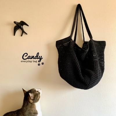 Saco de malha preto pendurado na parede com gato a olhar