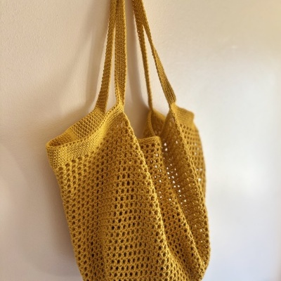 Mala de malha amarela pendurada com padrão de crochet