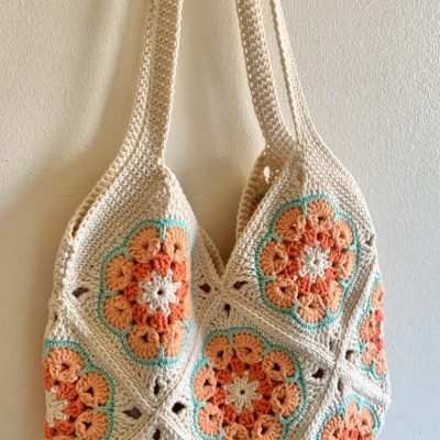 Saco de crochet com padrão floral em tons de laranja e azul claro