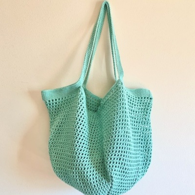 Saco de crochet verde água pendurado na parede