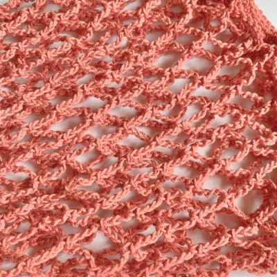 Pano de malha em croché cor coral com padrão de pontos abertos.