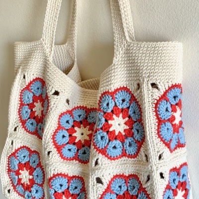 Bolsa de crochet creme com padrão floral vermelho e azul