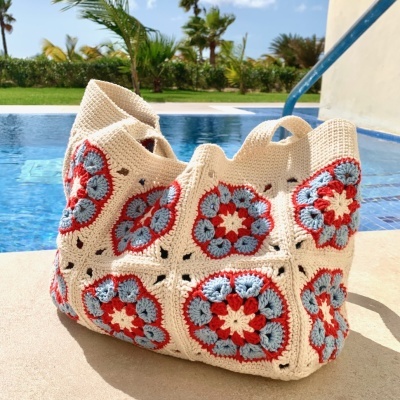 Bolsa de crochet creme com padrões florais junto a piscina ao ar livre