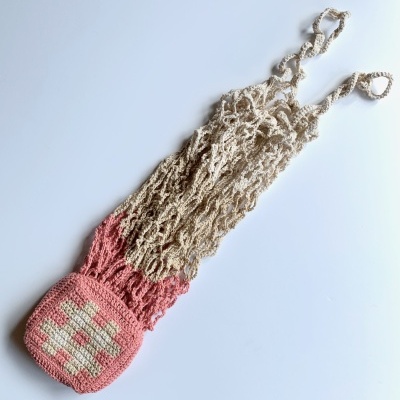 Saco de rede de malha rosa e bege com pegador redondo, fundo branco