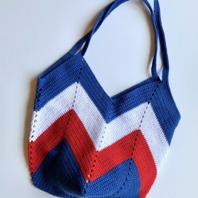 Mala tricotada azul, branca e vermelha com padrão zig-zag e alças