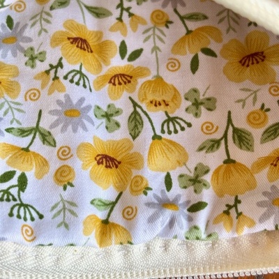 Tecido floral amarelo e verde com zíper branco numa mesa de madeira