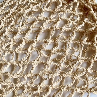 Detalhe de mala de crochê bege com padrão aberto