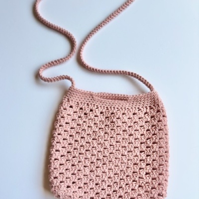 Bolsa de ombro rosa claro em crochet com padrão de malha aberta