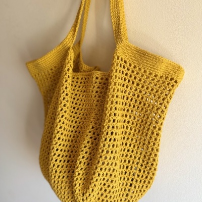 Saco amarelo de malha com padrão de pontos largos pendurado na parede