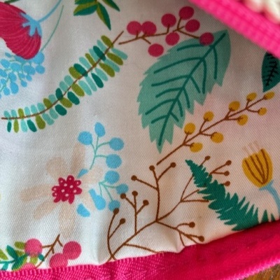 Interior de bolsa com tecido floral colorido e fecho rosa