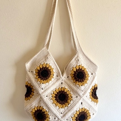 Saco de croché com padrão de girassóis, tons bege, castanho escuro e amarelo.