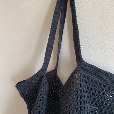 Saco de malha cinzento escuro com alças pendurado na parede