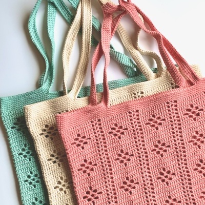 Três sacos de croché coloridos com padrão floral e alças duplas