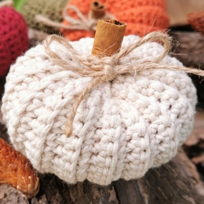 Abóbora decorativa de crochet branco com pau de canela e fio de juta em superfície de madeira