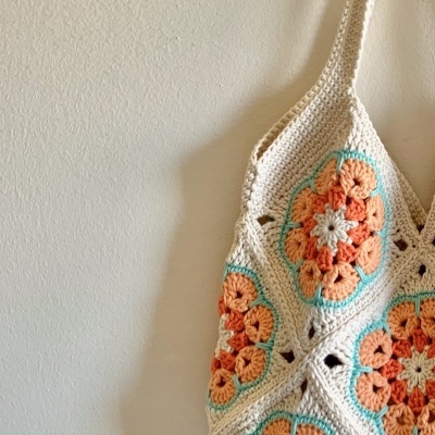 Bolsa de ombro em crochet bege, coral e verde-água pendurada na parede