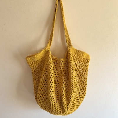 Saco de malha amarelo mostarda pendurado na parede