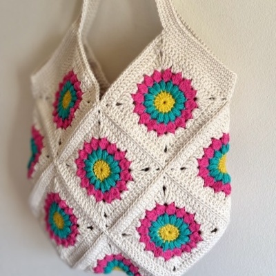 Mala de crochet branca com flores coloridas pendurada na parede