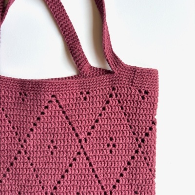 Saco de malha vermelho-rosado com padrão de diamantes e alças iguais ao corpo.