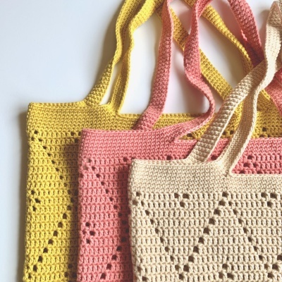 Malas de croché amarelo, rosa e bege com padrão geométrico e alças trançadas